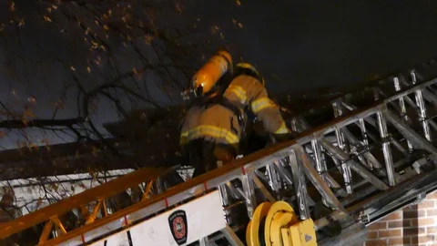 Firefighters climbing ladder during fire at night Stock Footage 103246451