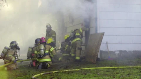 Firefighters crouch by a burning house Stock Footage 60737112