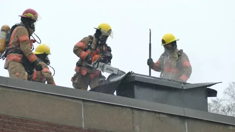 Firefighters cutting chimney with chainsaw Stock Footage 139664314
