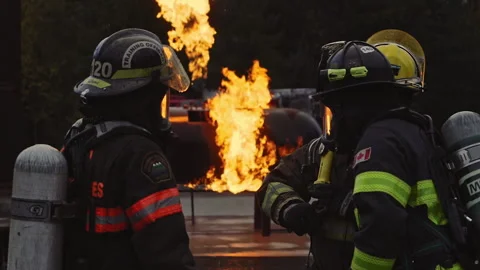 Firefighters discussing training routine in front of roaring fire Video stock 168460568