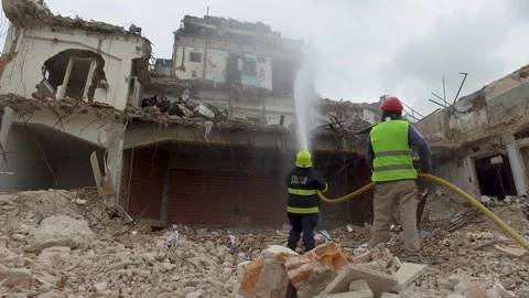 Firefighters dousing smoldering ruins of a collapsed building, debris Stock Footage 263193861