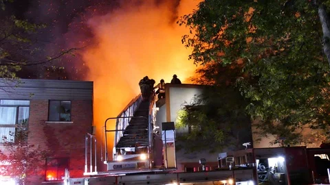 Firefighters escalading ladder with flames and structure fire Stock Footage 116084435