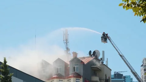 Firefighters extinguish burning house using extended ladder equipped with water Stock Footage 282380740