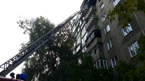 Firefighters extinguish a fire on the balcony of a high-rise building in th.. Stock Footage 256754846
