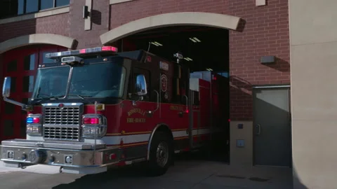 Firefighters in a firetruck pull out from a fire station for an emergency Stock Footage 232650467