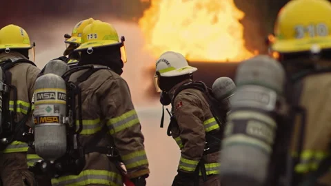 Firefighters in formation spraying fire with hose in slow motion - dramatic Stock Footage 168461576