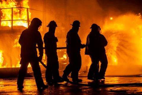 Firefighters hosing down fire Stock Photos
