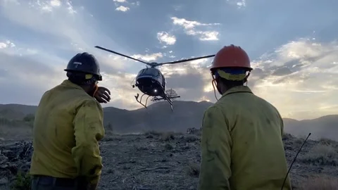 Firefighters Observing Helicopter in Action Stockbeeldmateriaal 348156147