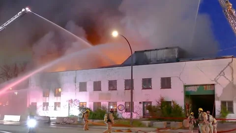 Firefighters organizing hoses during a fire in a warehouse and using fire truck Stock Footage 294362781