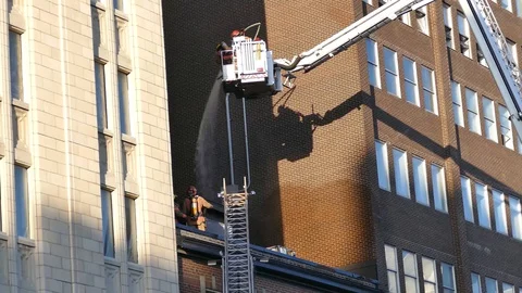 Firefighters on a platform splashing building with water Stock Footage 90360150