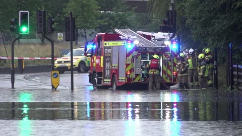 Firefighters prepare a fire engine to pump water out from a flooded road Stock Footage 157953795