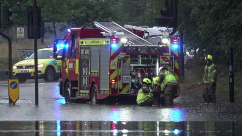 Firefighters prepare a fire engine to pump water out from a flooded road Stock Footage 157954036