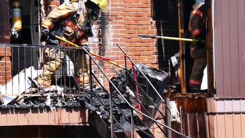 Firefighters pushing burned air conditioner to the ground Stock Footage 90337108