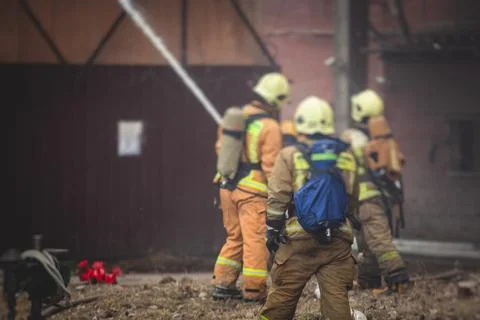Firefighters put out large massive fire blaze, group of fire men in uniform d Stock Photos