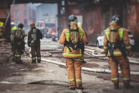 Firefighters put out large massive fire blaze, group of fire men in uniform d Stock Photos