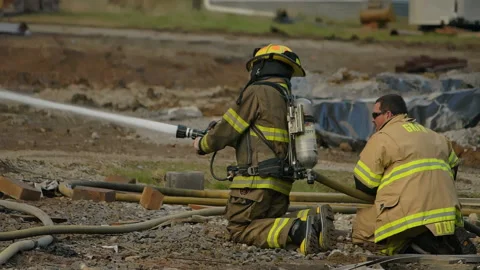 Firefighters putting out a large fire with a fire hose. Slow motion video Stock Footage 229816745
