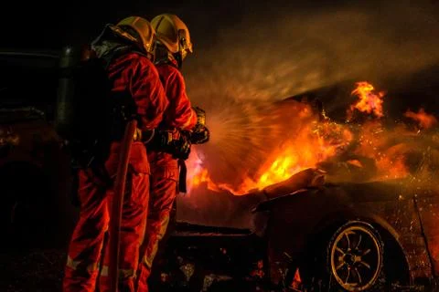 Firefighters spraying down fire flame from car accident Stock Photos