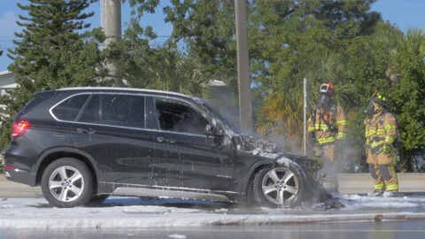 Firefighters Stand Next to Smoldering SUV Stock Footage 169749751