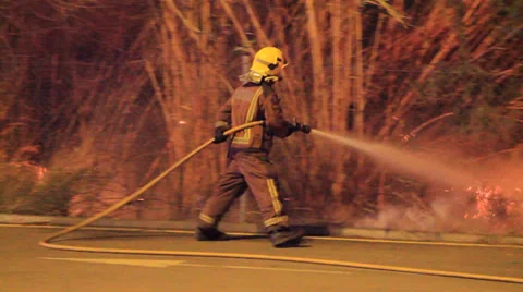Firefighters try to douse a fire started very near of housings Stock Footage 34450986