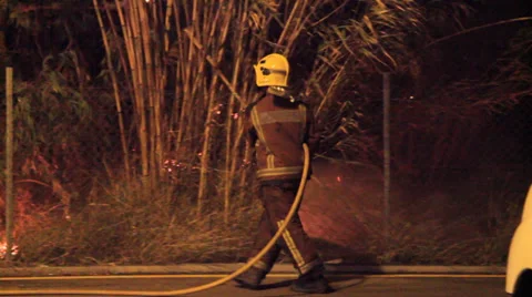 Firefighters try to douse a fire started very near of housings Stock Footage 34451802