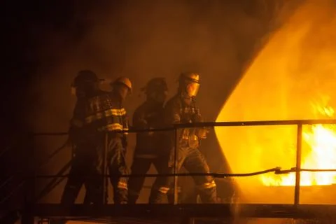 Firefighters using full spray to put out fire during firefighting exercise Stock Photos