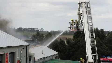 Firefighters using hoses to fight a fire on a roof Video stock 107672420