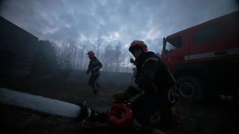 Firefighters using water to extinguish open air fire Stock Footage 283176097