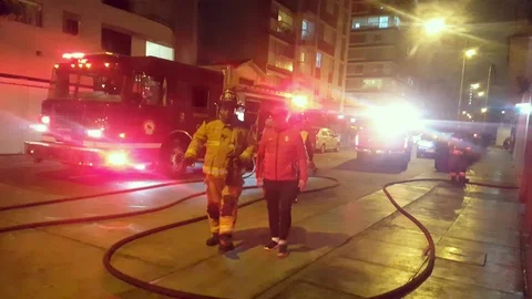 Firefighters walking between hoses and fire trucks Stock Footage 116619305