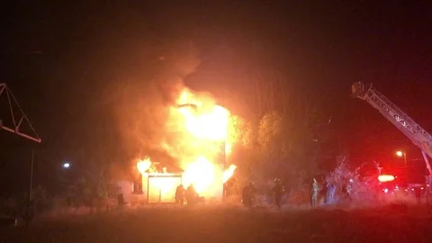 Firefighters work to put out house fire with police lights and fire blazing Stock-Footage 129585139