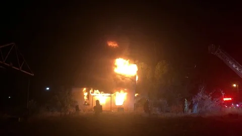 Firefighters work to put out house fire with hoses and emergency lights Stock-Footage 129585168