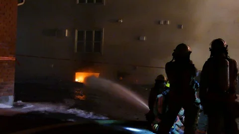Firefighters working at basement fire with flames at night Stock Footage 125230784