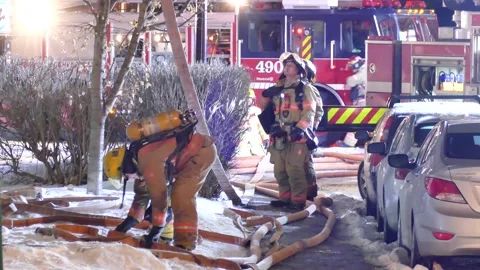 Firefighters working with hoses during snowy night Stock Footage 139663843