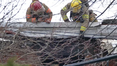 Firefighters working on a house with their instruments during the day Stock Footage 89522729