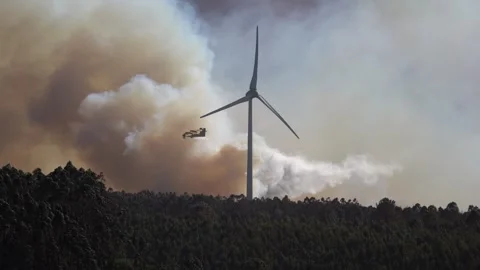 A firefighting airplane drops a large stream of water over a massive wildfire Stock Footage 317525748
