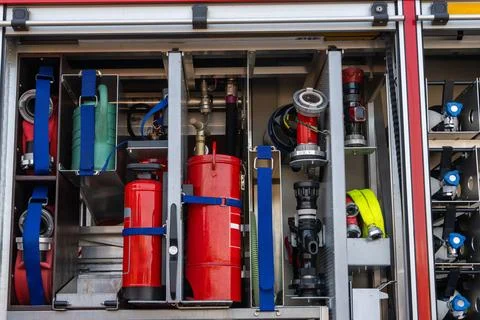 Firefighting equipment organized inside open fire truck compartment, extingui 스톡 사진