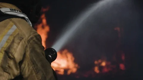 Fireman aiming hose at flames Stock Footage 91036685