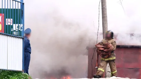 Fireman comes out of the fire and carries the fire hose in his hands. Stock Footage 109388742