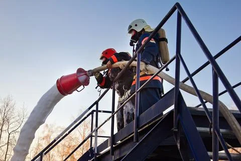 Fireman extinguish fire by foam spraying hose Stock Photos