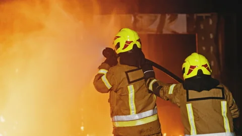 Fireman extinguish fire with the hose. Burning house fire drill Stock Footage 140644832
