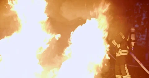 Fireman in full equipment putting out the fire in the middle of the night Stock Footage 125144859