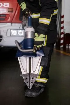 Fireman holding a pair of pneumatic scissors in a fire station Stock Photos