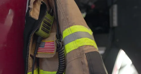 Fireman jacket known as bunker or turnout safety gear hanging on firetruck Stock Footage 289868416