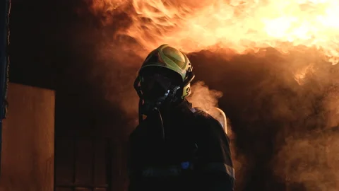 Fireman or fire fighter stand in front of big fire on wall of kitchen and heat Stock Footage 156979330