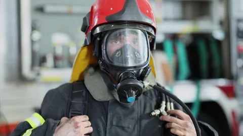 Fireman poses in protective suit, red helmet and gas-mask Stock Footage 276368513