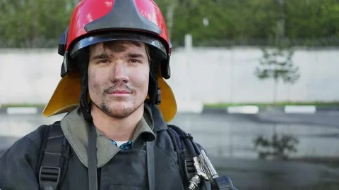 Fireman poses in red fire helmet and closes face protective glass. Slow motion Stock Footage 276368551