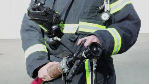 Fireman in protective suit and helmet holds hose with seeping water Stock Footage 276368505