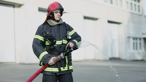 Fireman in protective uniform adjusts water stream from hose Stock Footage 276368492