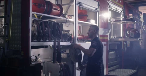 Fireman putting hoses into fire engine Stock Footage 138520876