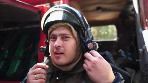 Fireman in uniform putting oxygen mask against background of a big red truck Video stock 304116706