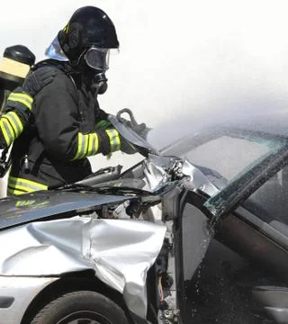 Fireman uses a shear to open the sheets of a damaged car Фото